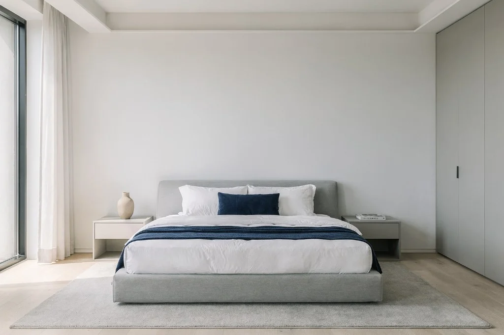 Chambre moderne avec un grand lit aux draps blancs et coussins bleus, environnement de test réaliste